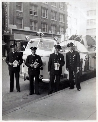 Captain Asbury Bice and other members of the Fort Worth Fire Department stand in front of ladder truck in the mid-1950s across the street from The Camera Shop, 709 Throckmorton - believed to be the first ladder truck in the FWFD