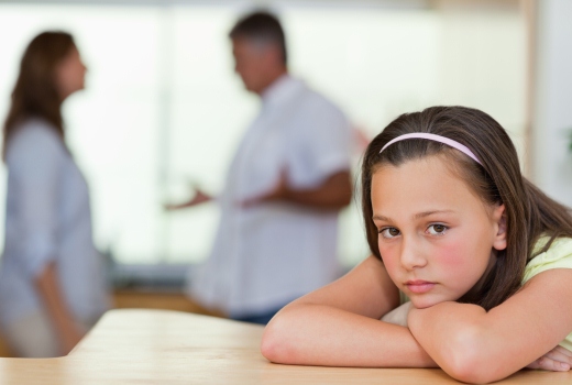 Sad girl with parents arguing behind