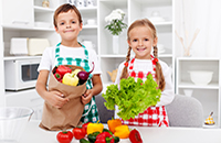 Boy, girl with colorful aprons handling grocieries