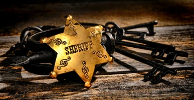 Image of an antique brass badge with the word Sheriff across it and keys