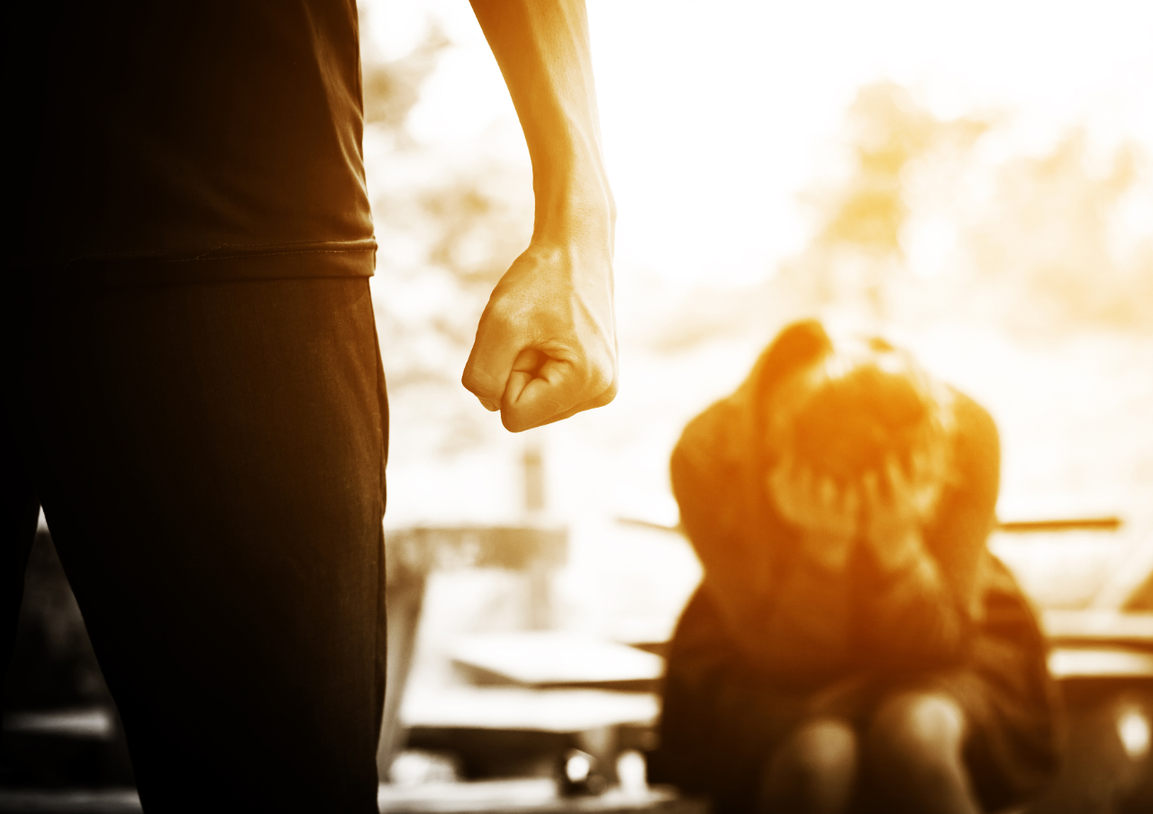A photo of a person making a fist with a woman covering her face.