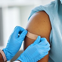 Physician placing an adhesive bandage on patient