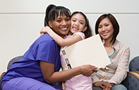 ethnic mother, daughter hugging black nurse