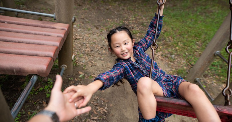 father reaching out to help daughter falling off swing