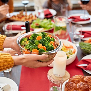 hands holding a healthy veggie dish over festive table