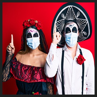 Day of the Dead couple with painted faces wearing costumes, protective masks